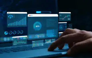 person using a laptop with data dashboards, charts, and reports displayed above the keyboard