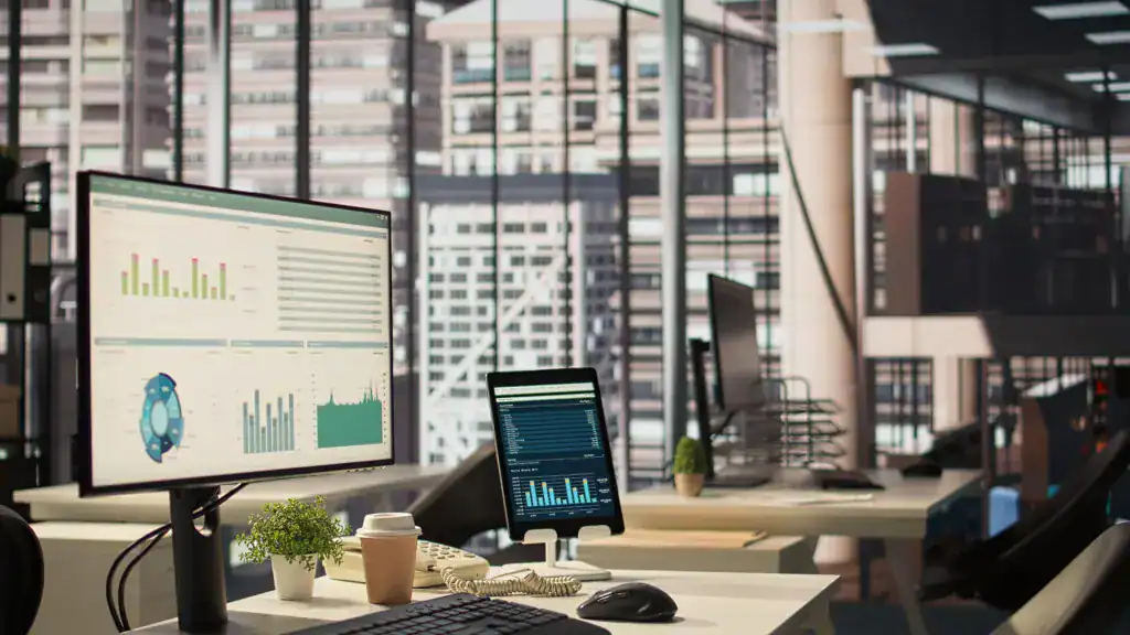 Modern office workspace displaying business intelligence dashboards and reporting metrics on multiple screens