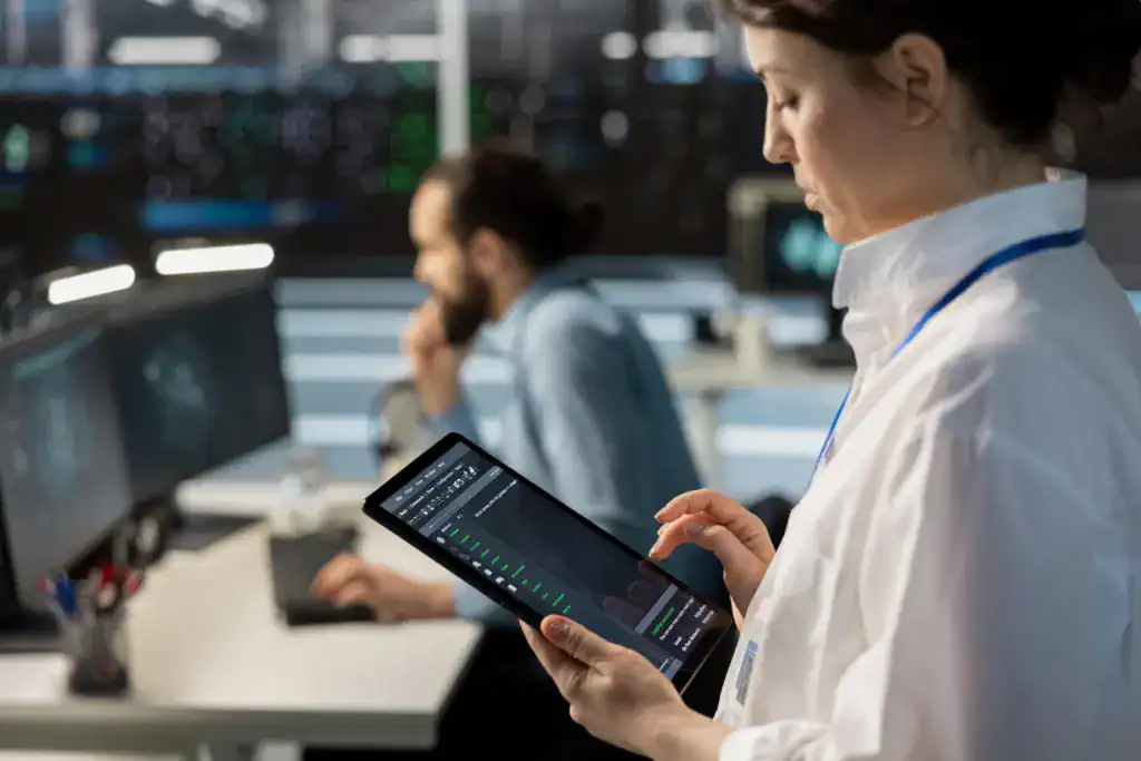 Woman reviewing a data dashboard on a tablet while standing in a server room
