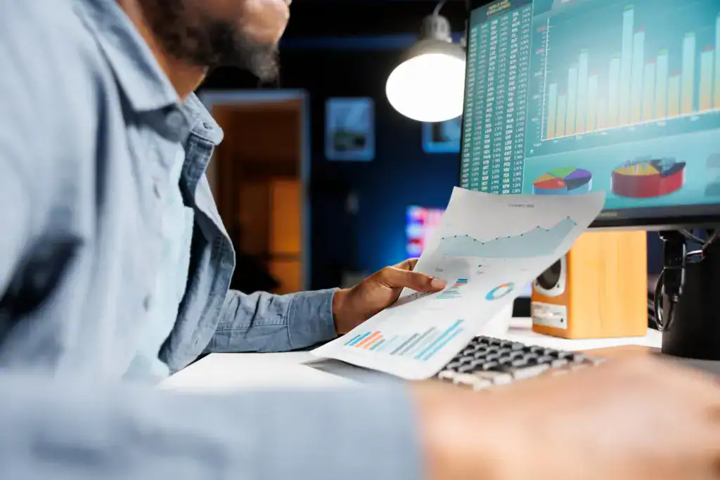 Business professional reviewing reports beside a data dashboard