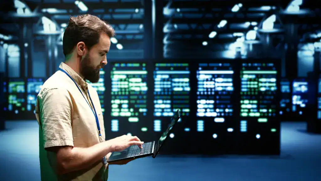 IT professional using a laptop to monitor systems in a data centre