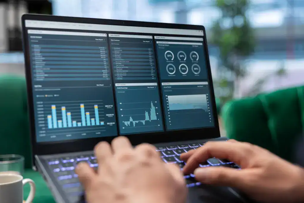 Professional working on a laptop displaying financial charts and performance metrics